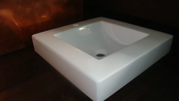 Lavabo de sobre encimera cuadrado de cerámica blanca.